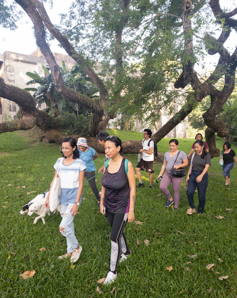 A group of men and women walks under a tree