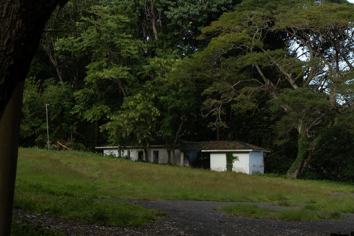 White camp houses under trees behind a grass field
