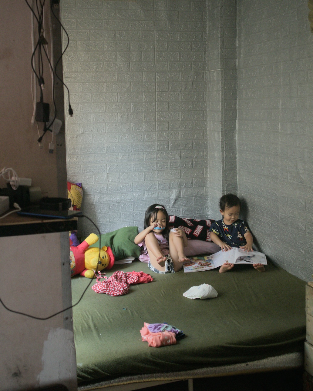 Two children reading books while on bed