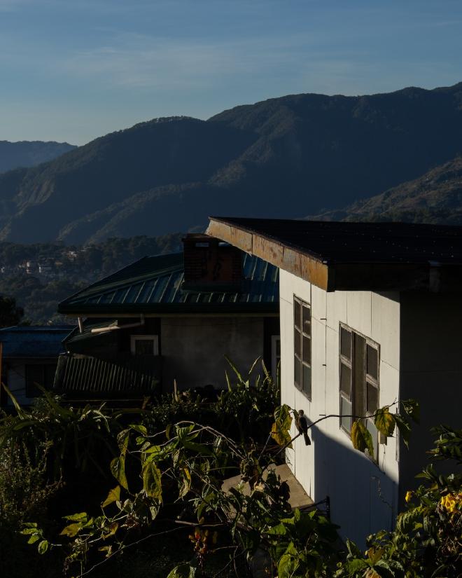 A sunlit house with mountains in the background