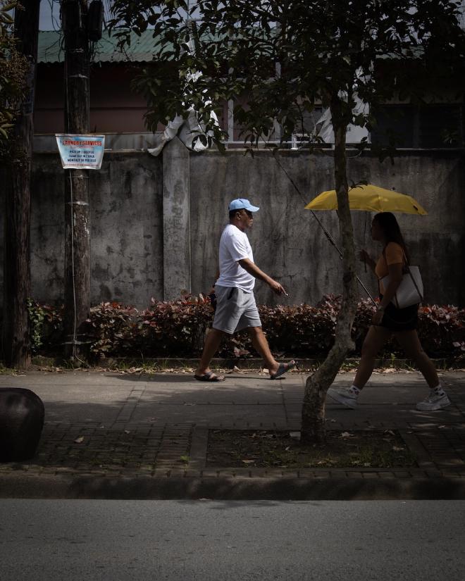 Man with a cap waling on the sidewalk