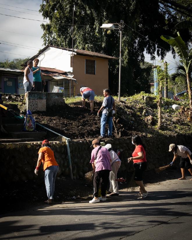 A group of people cleaning the side of the road with brooms